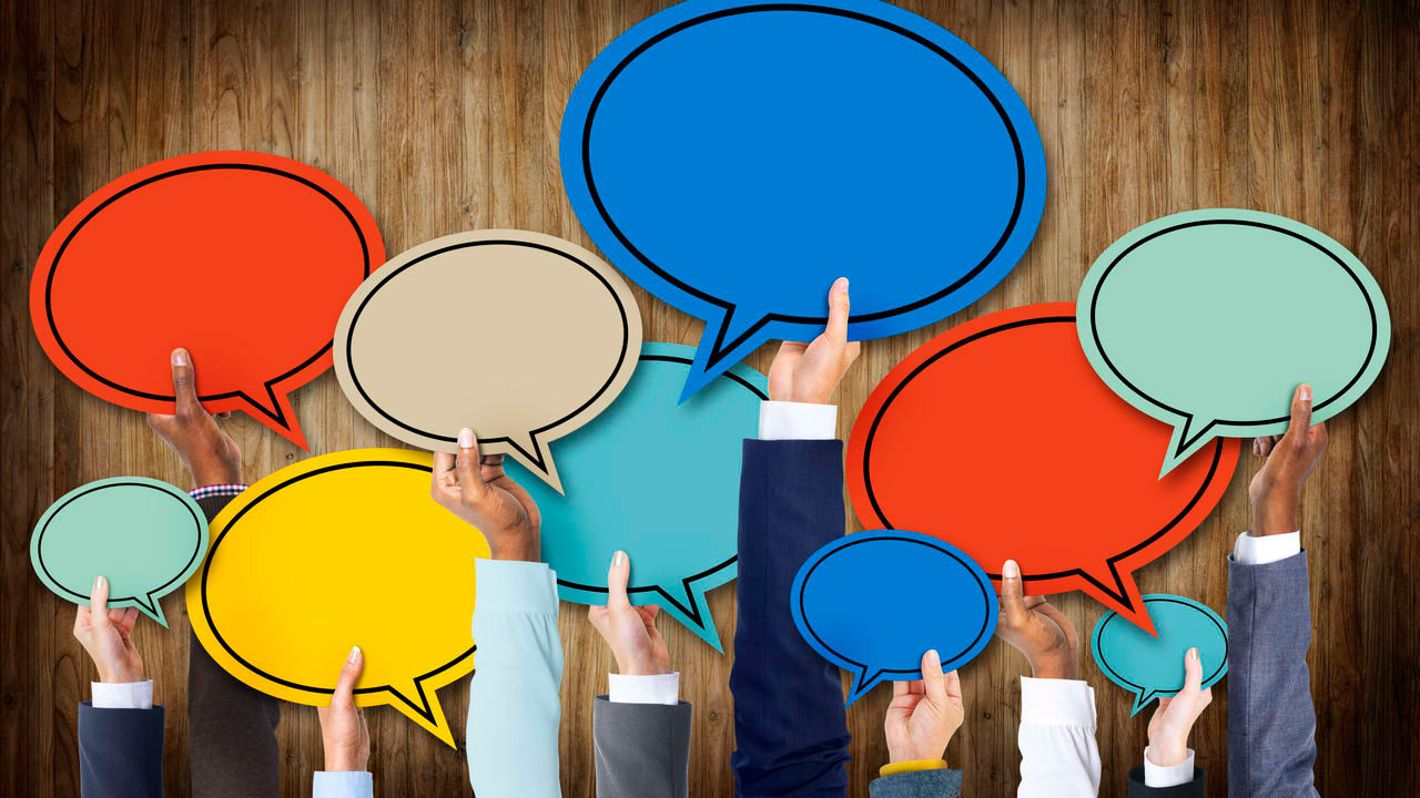 A group of business people holding up speech bubbles on a wooden background.