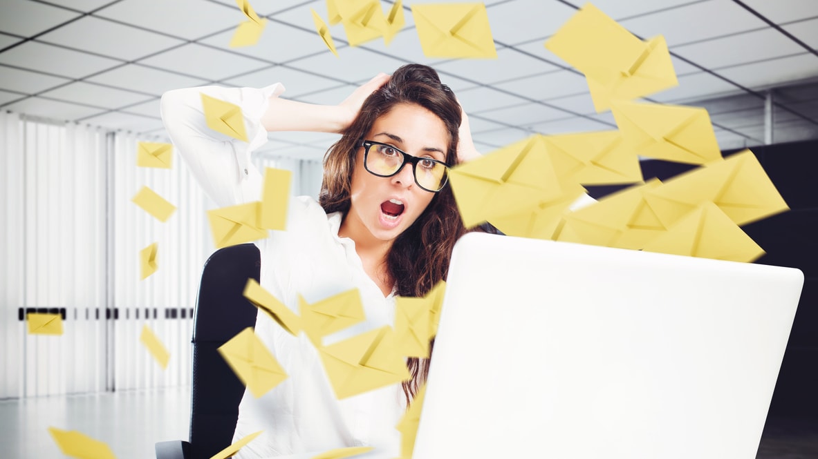 A woman is sitting in front of a laptop with mail coming out of it.