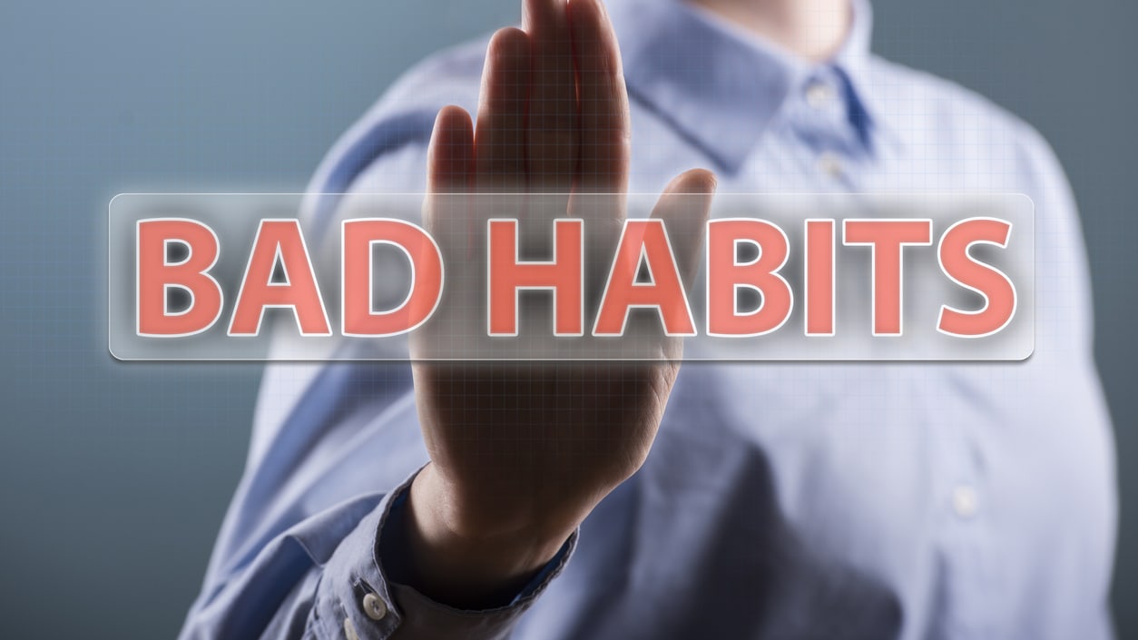 A man is holding up a sign that says bad habits.