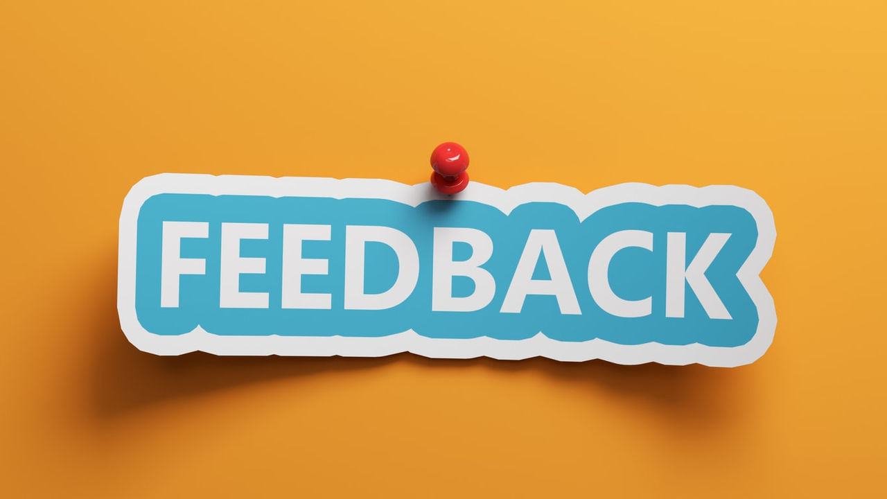 A blue paper with the word feedback hanging on an orange background.
