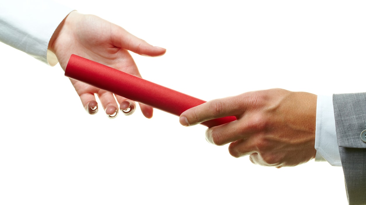 A businessman handing a red pen to another person.