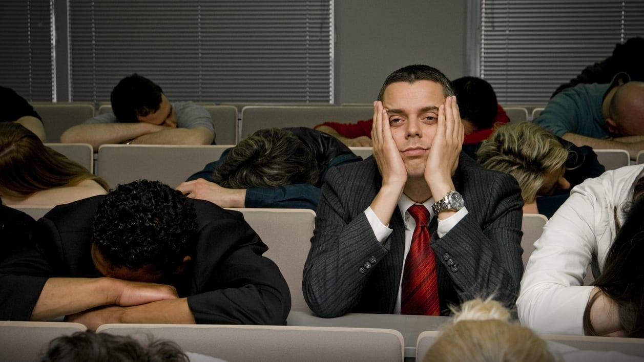 A group of people sleeping in a lecture hall.