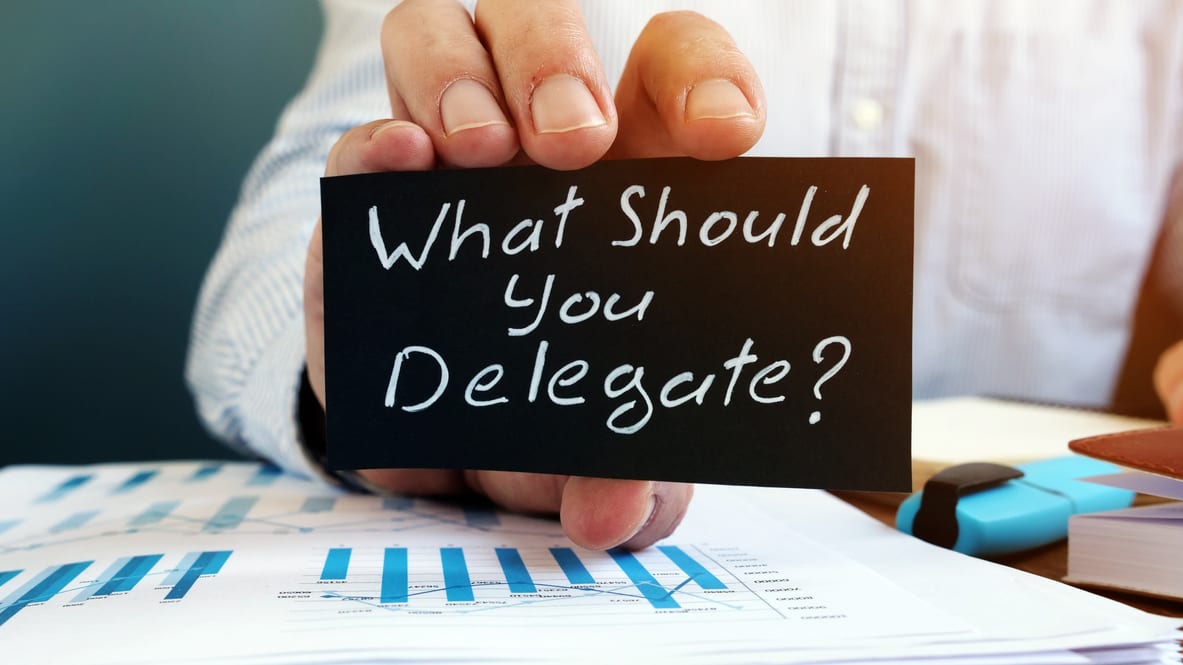 Man holding a note that says what should you delegate?
