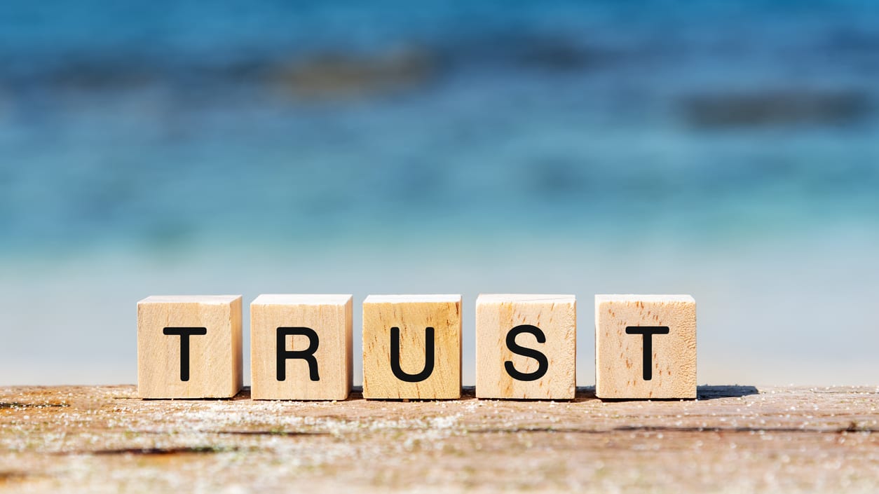 The word trust spelled out in wooden blocks on a wooden table.