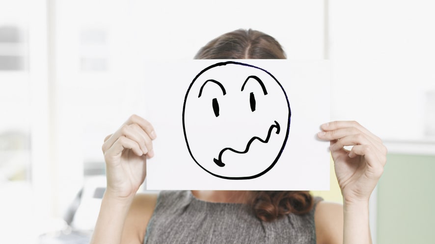 A woman holding up a paper with a smiley face on it.