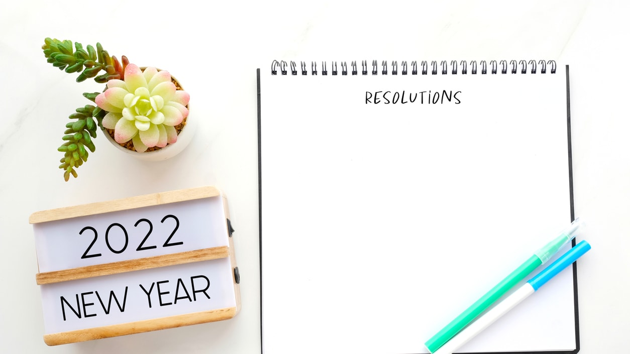 A notebook with a new year's resolution on it and a plant next to it.