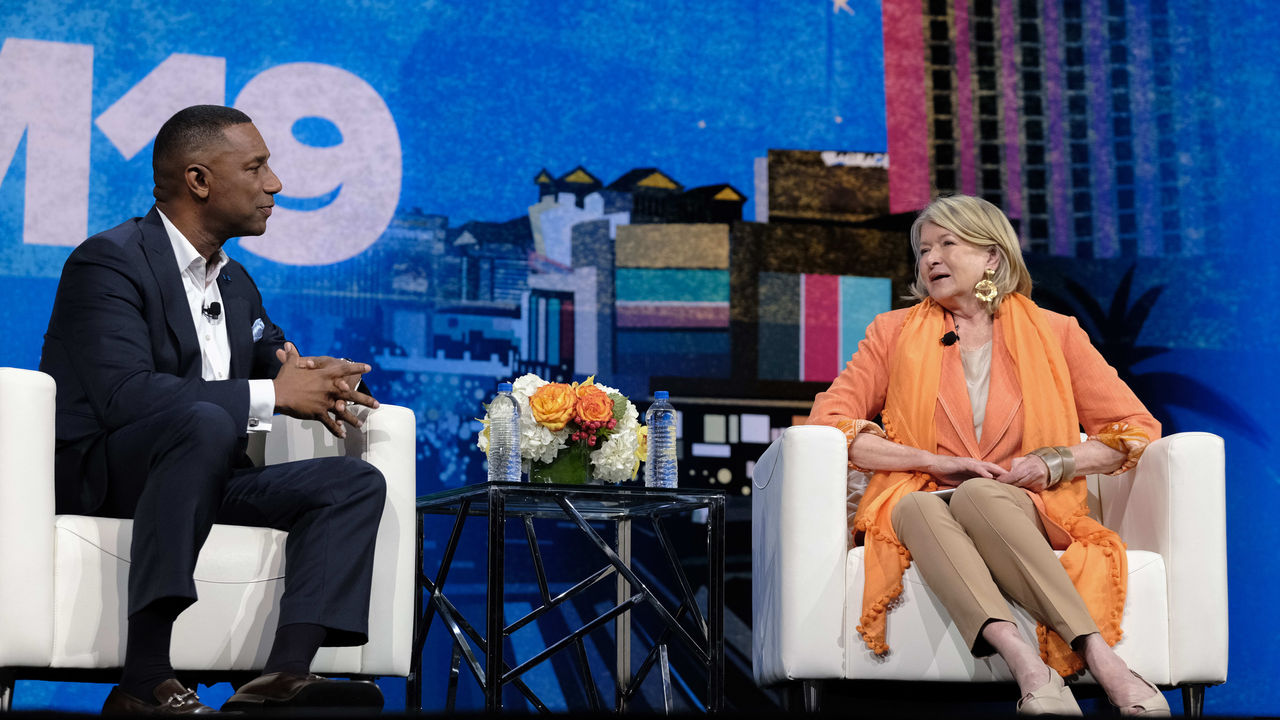 A man and woman sitting in chairs on a stage.