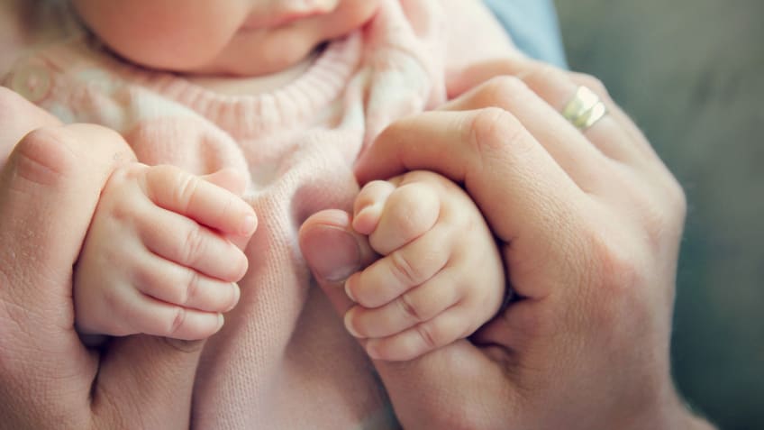 A baby's hands are being held by someone's hands.