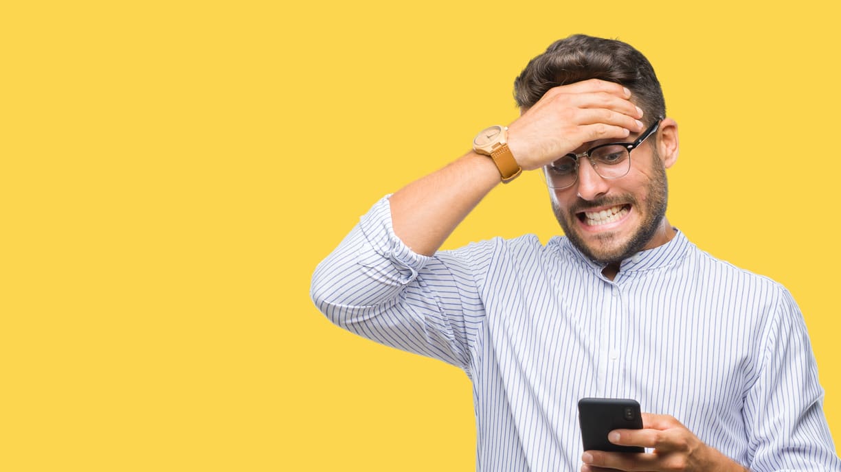 A man looking at his phone on a yellow background.