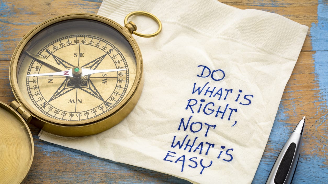 A compass laying on top of a napkin that has the words "Do what's right, not what's easy" written on it.