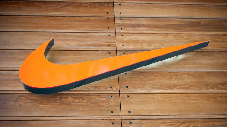 An orange and black nike logo on a wooden wall.