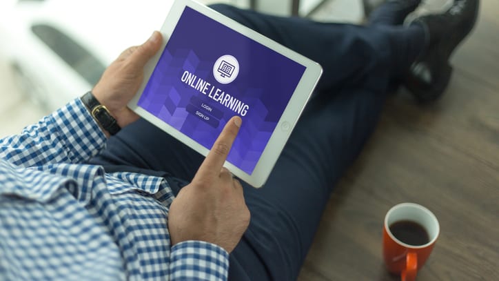 A man holding an ipad with the word online learning on it.