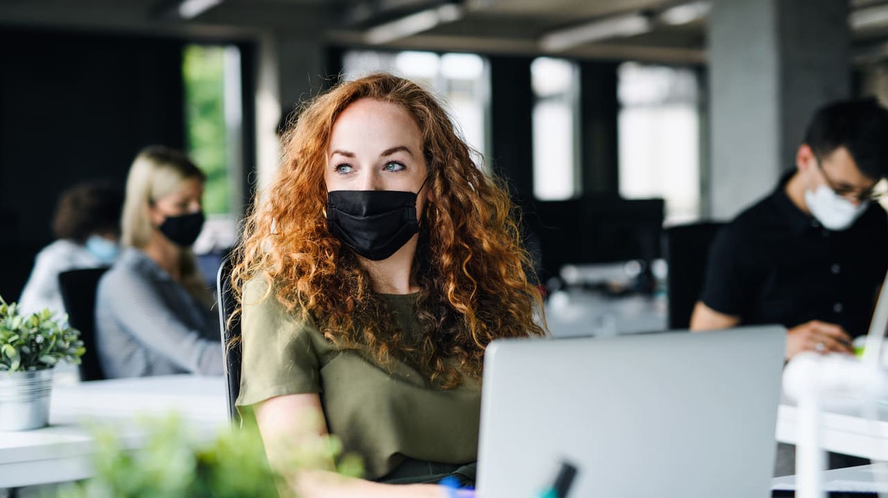 A woman wearing a face mask in an office.