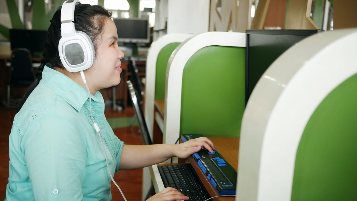 A woman wearing headphones is using a computer.