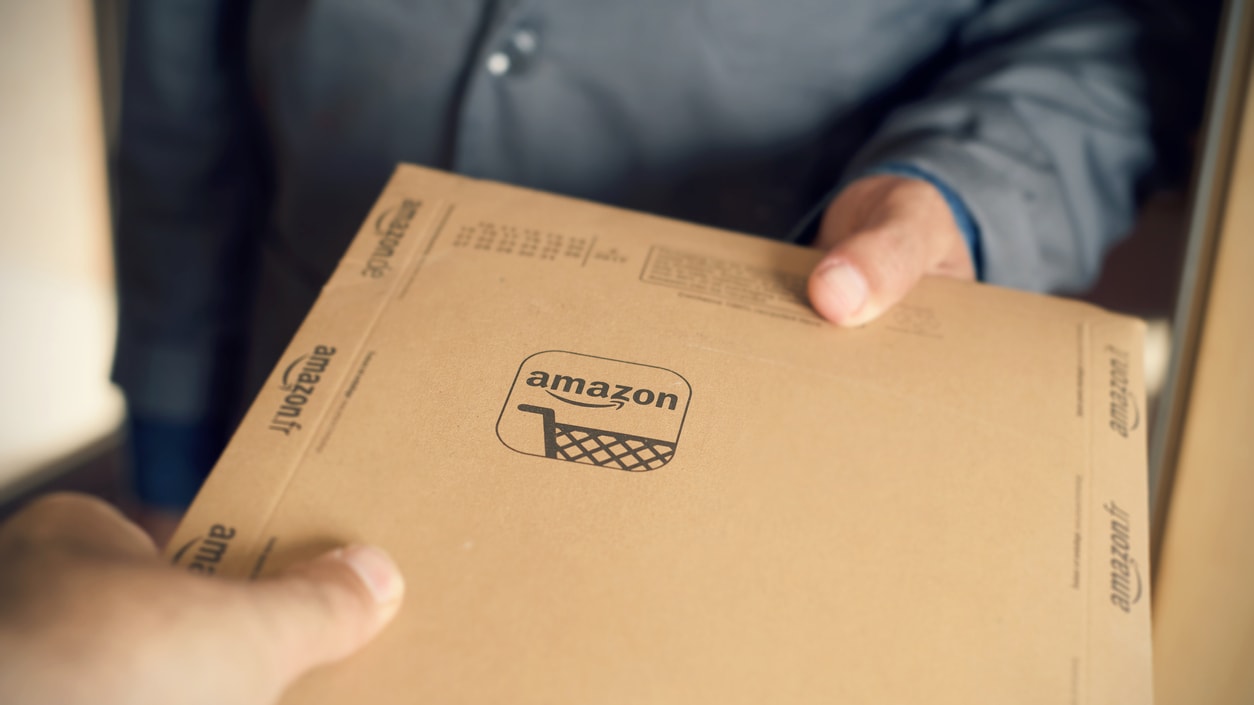 A person is handing an amazon box to another person.