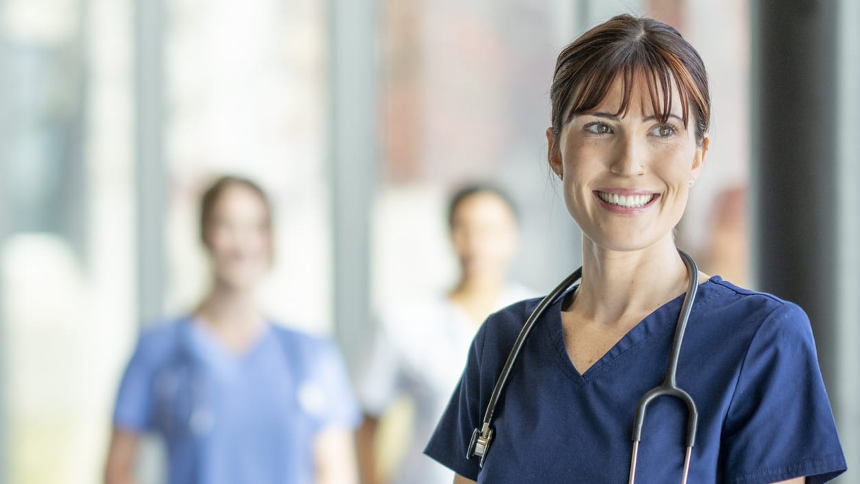 A nurse standing in front of a group of other nurses.