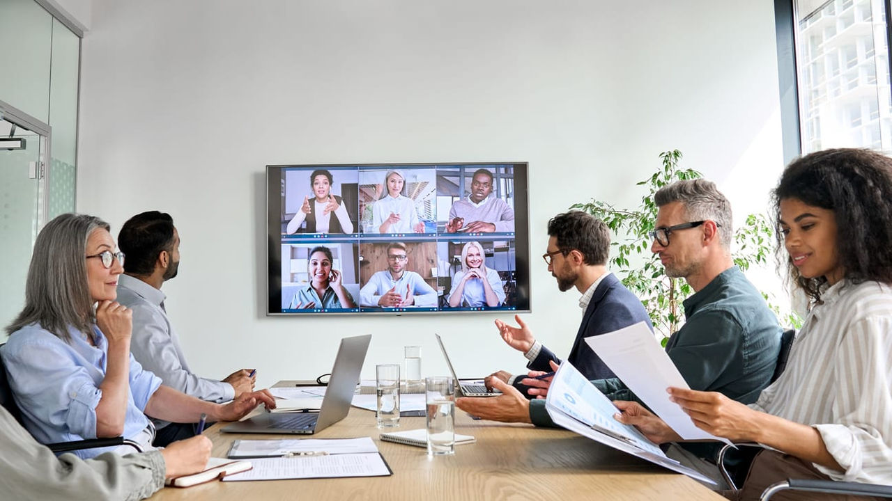 A group of people having a video conference in a conference room.