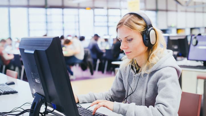 A woman wearing headphones is using a computer.