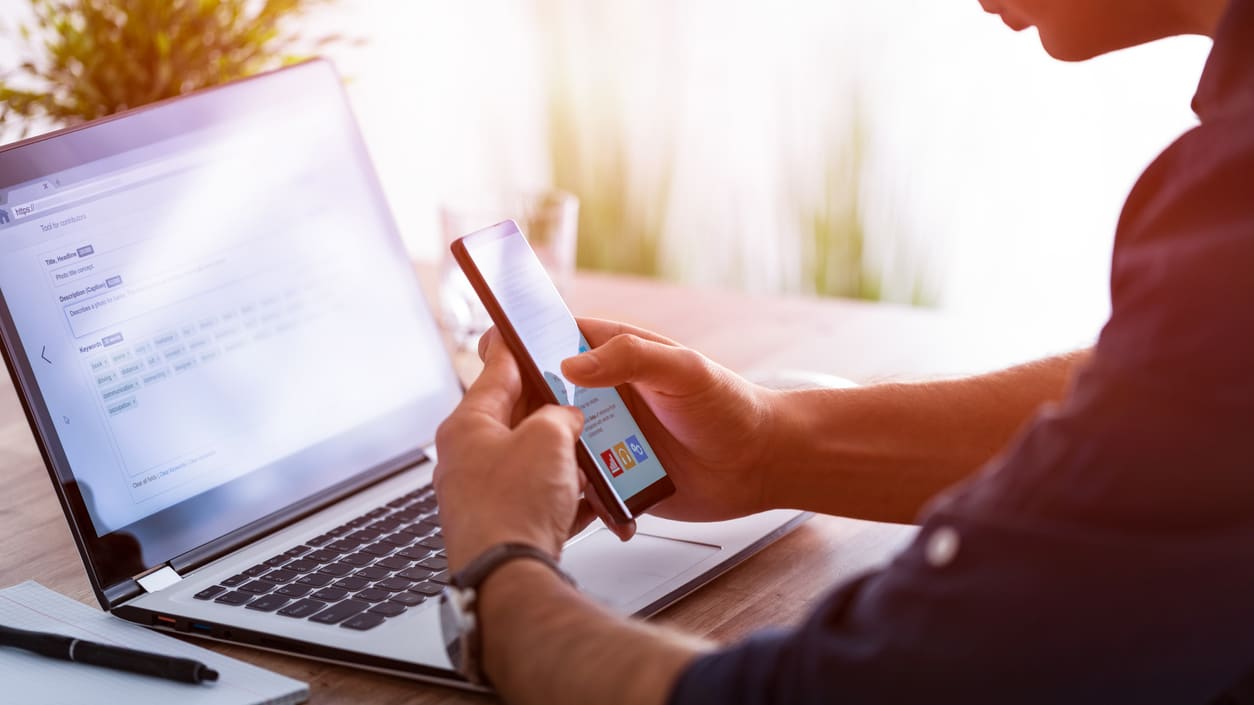 A man using a smartphone while sitting at a desk.