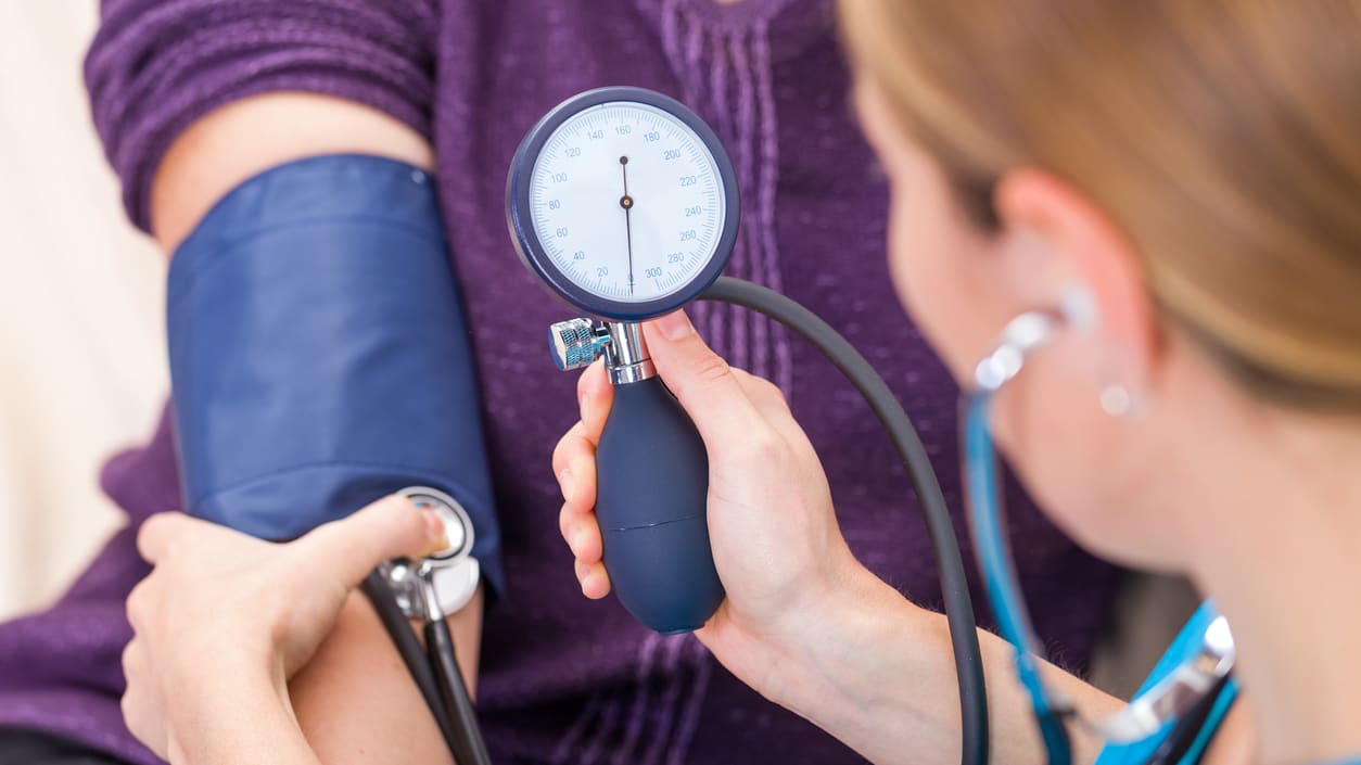 A woman is taking her blood pressure with a stethoscope.