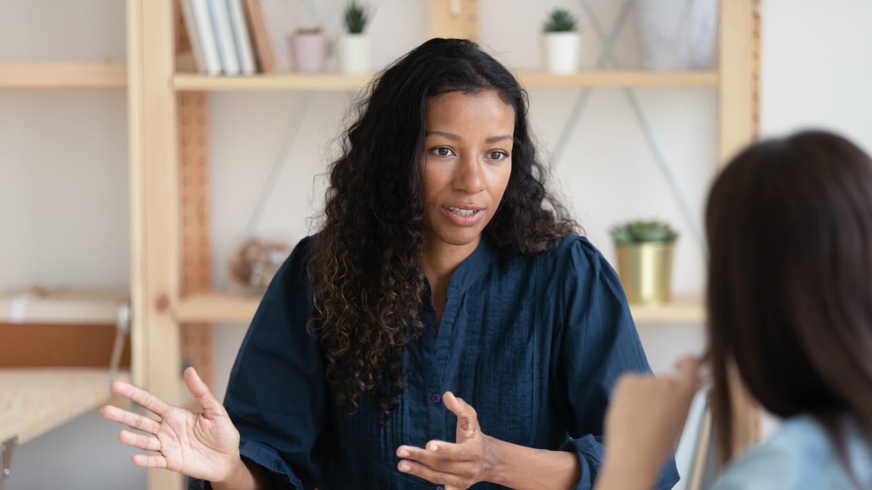 Two women talking at a table in an office.