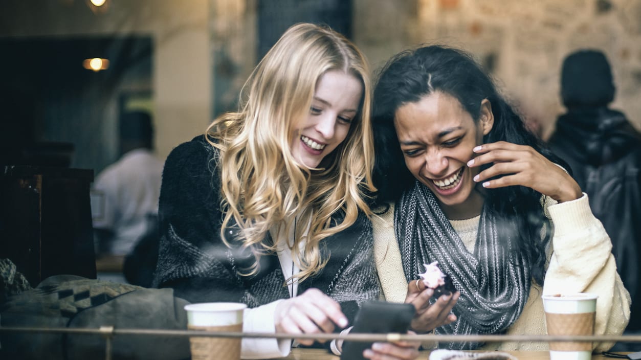 Two women looking at their phones in a coffee shop.