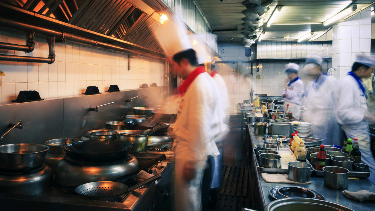 A blurry image of a group of cooks in a kitchen.