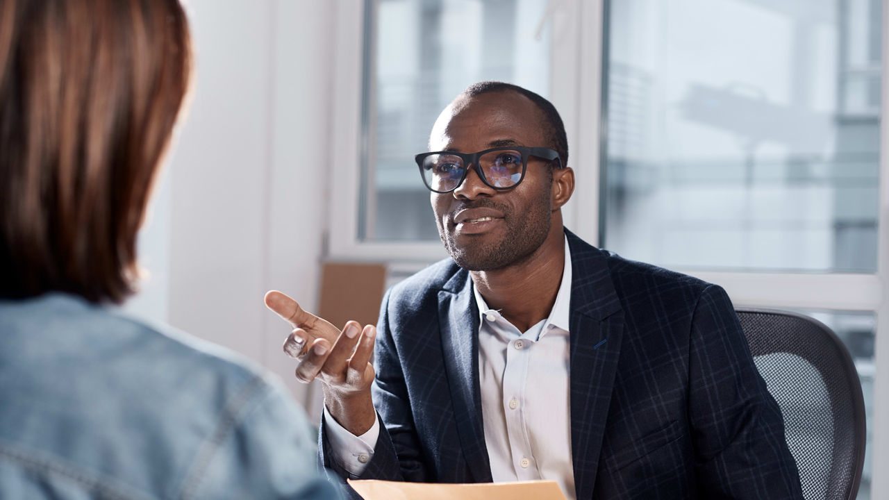 A man is talking to a woman in an office.