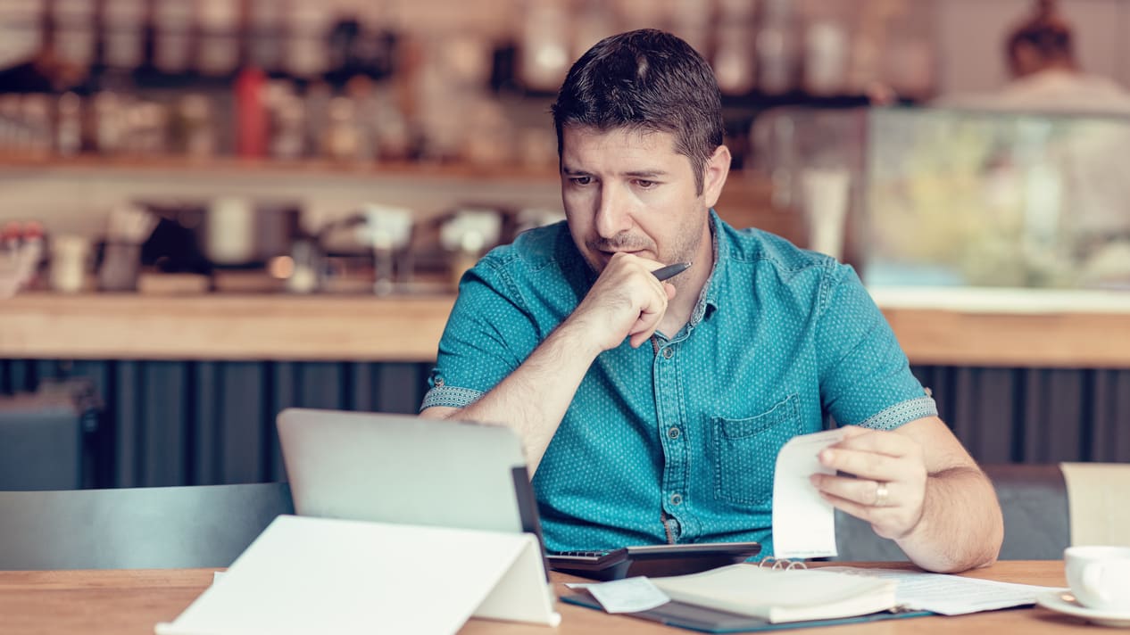 A man sitting at a table with a laptop and papers.