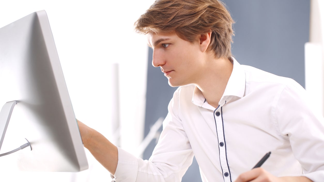 A young man looking at a computer screen.