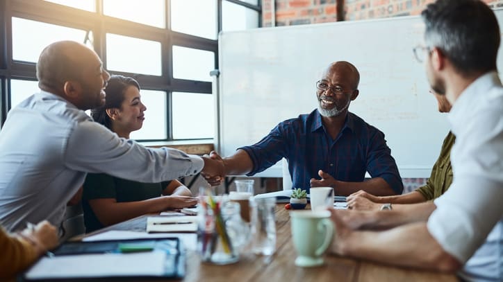 A group of people shaking hands at a meeting.