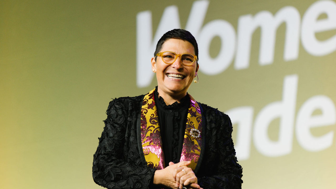 A woman in a suit standing in front of a sign that says women's leadership.