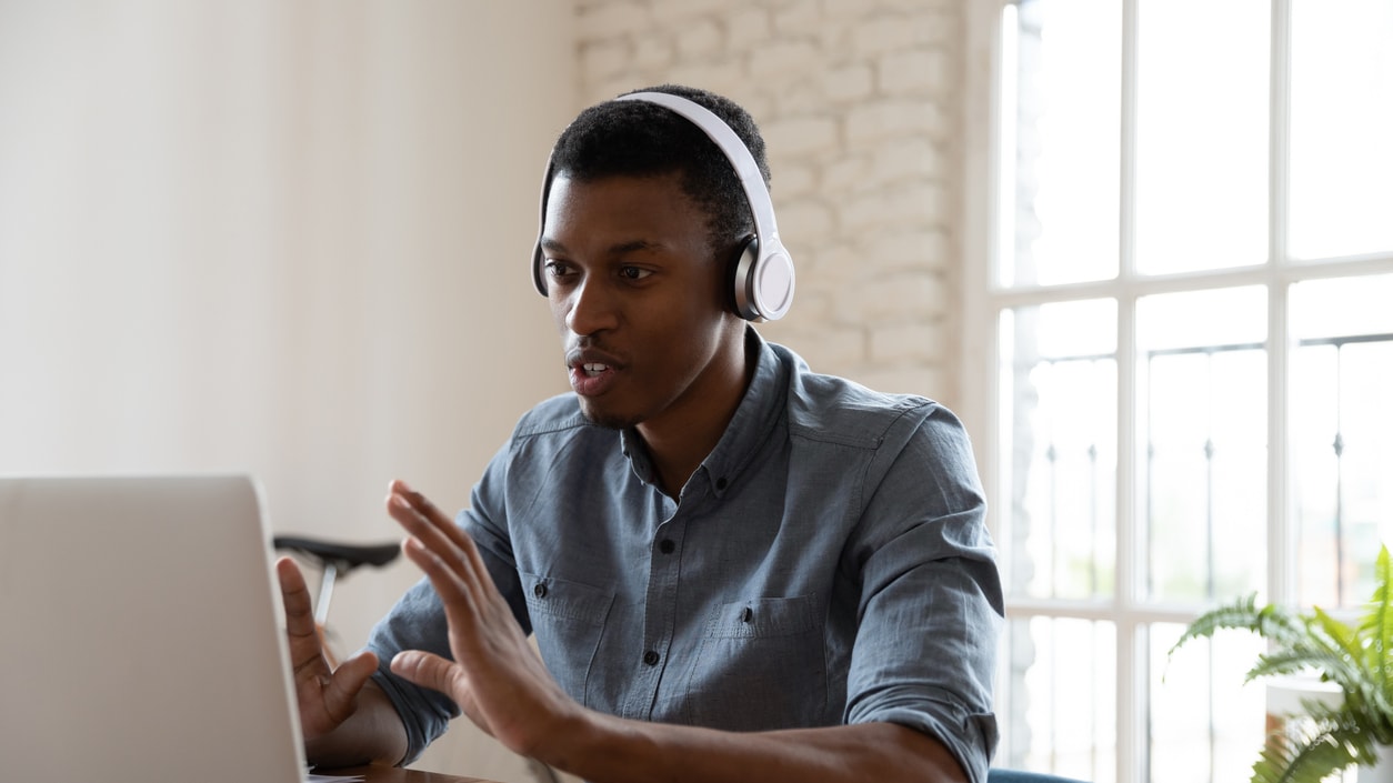 A young man using a laptop while wearing headphones.