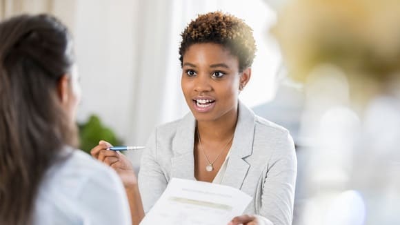 A woman is talking to another woman in an office.