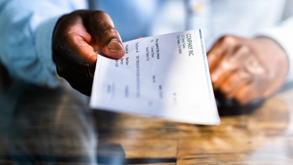 A man is holding a check on a table.