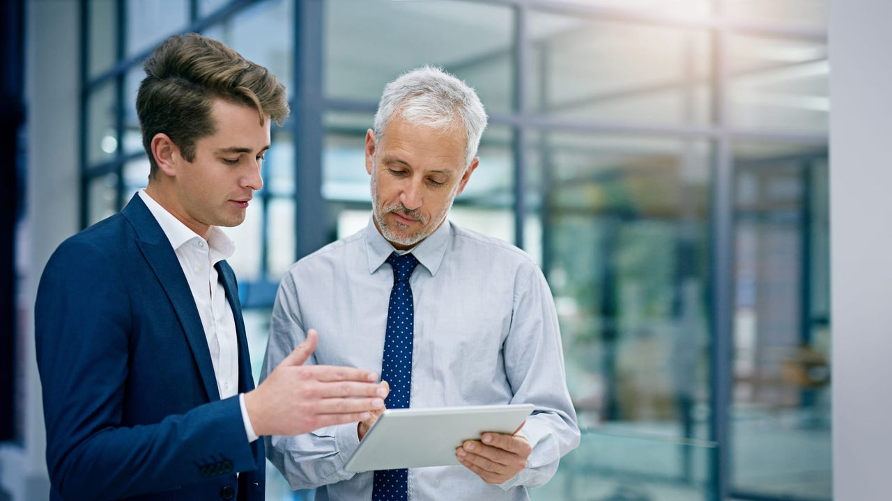 Two businessmen looking at a tablet in an office.