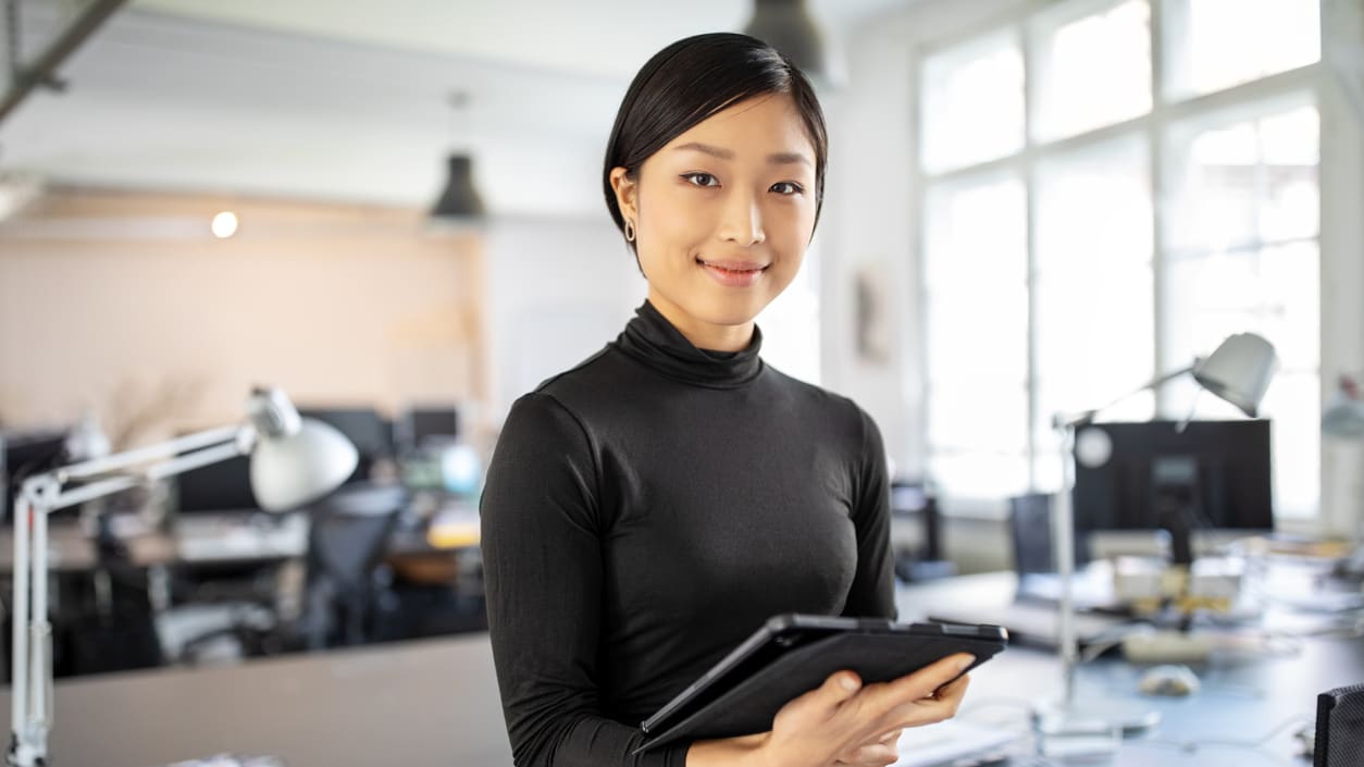 A young woman holding a tablet computer in an office.