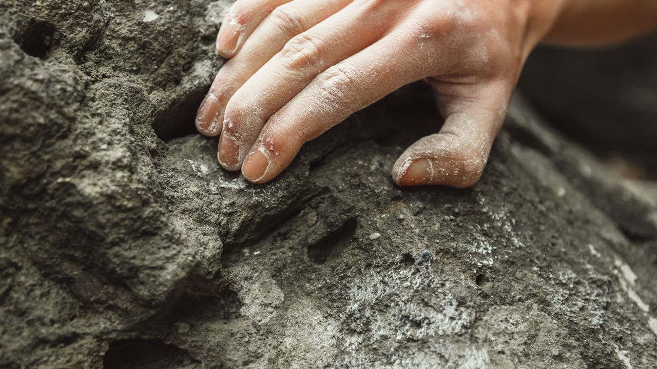 A person's hand on a rock climbing wall.