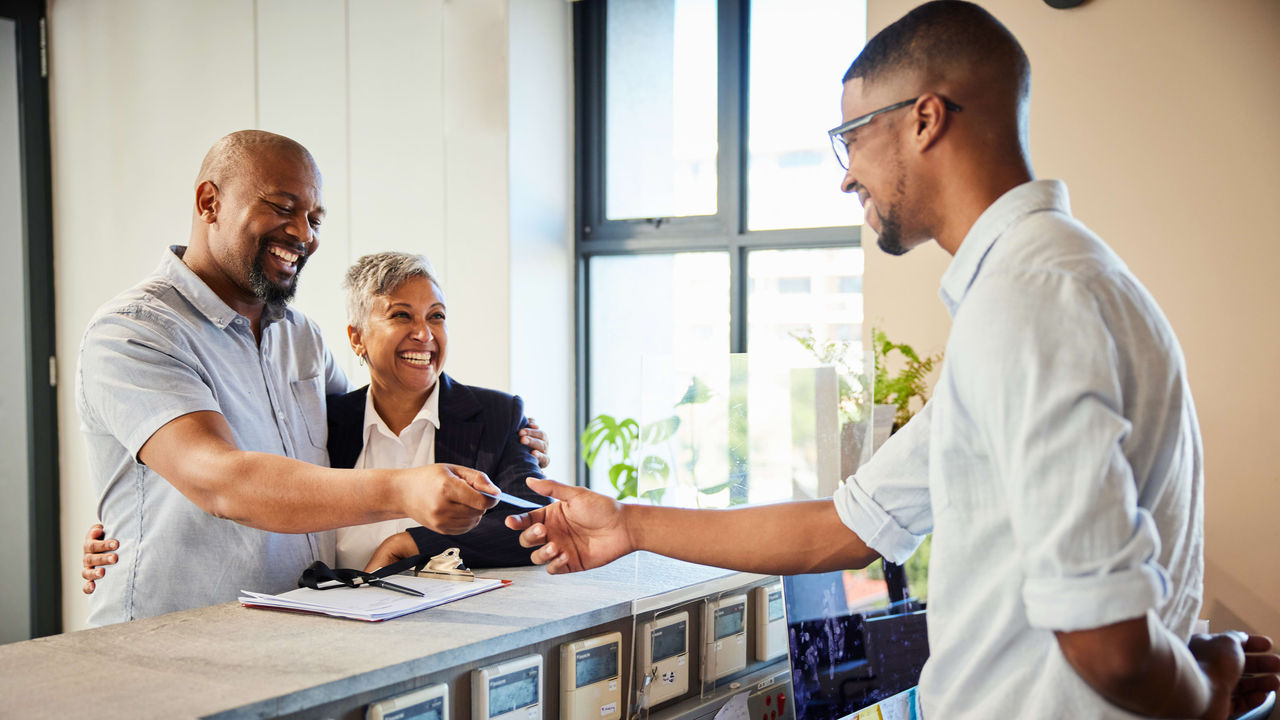 Two people shaking hands at a reception desk.