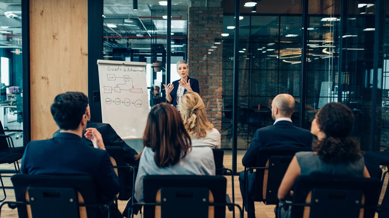 A woman is giving a presentation to a group of people in a conference room.