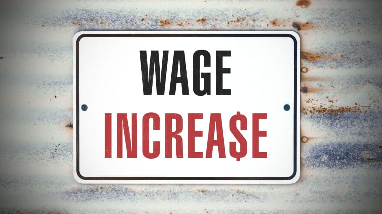 A sign that says wage increase on a rusty metal background.
