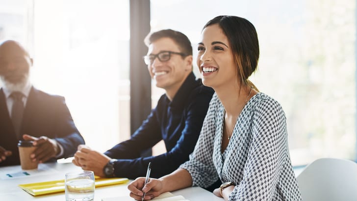 A group of business people sitting at a table and smiling.