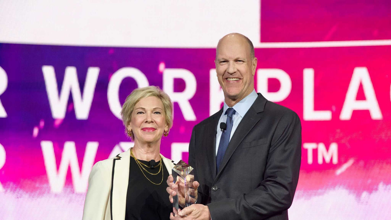 A man and woman standing next to each other holding an award at a conference.