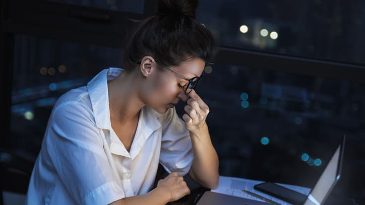 A woman is sitting in front of a laptop at night.