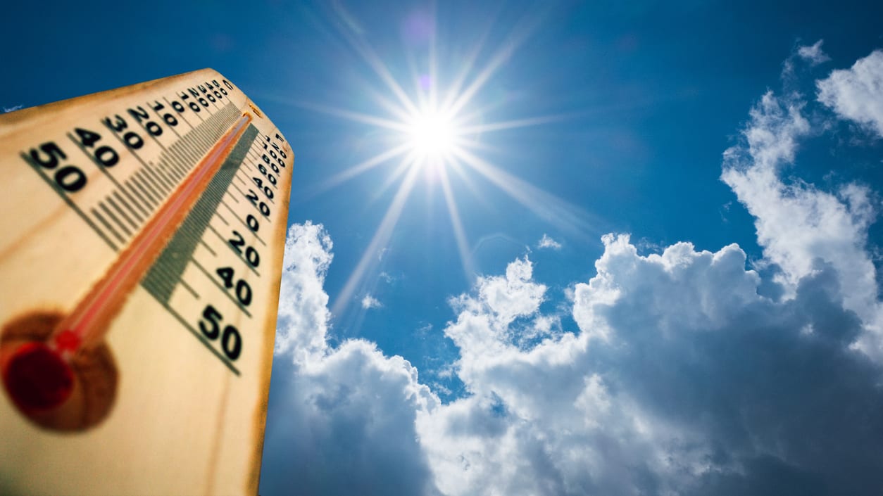 A thermometer is shown against a blue sky.
