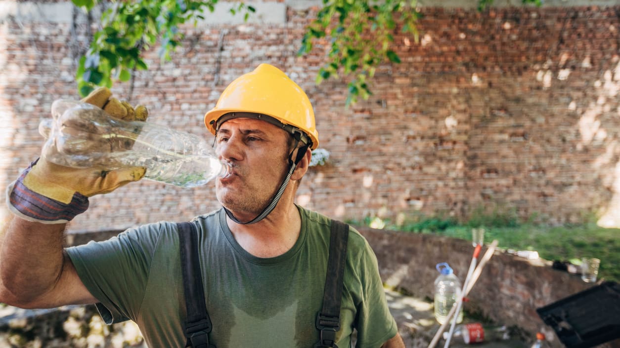 A construction worker drinking water from a bottle.