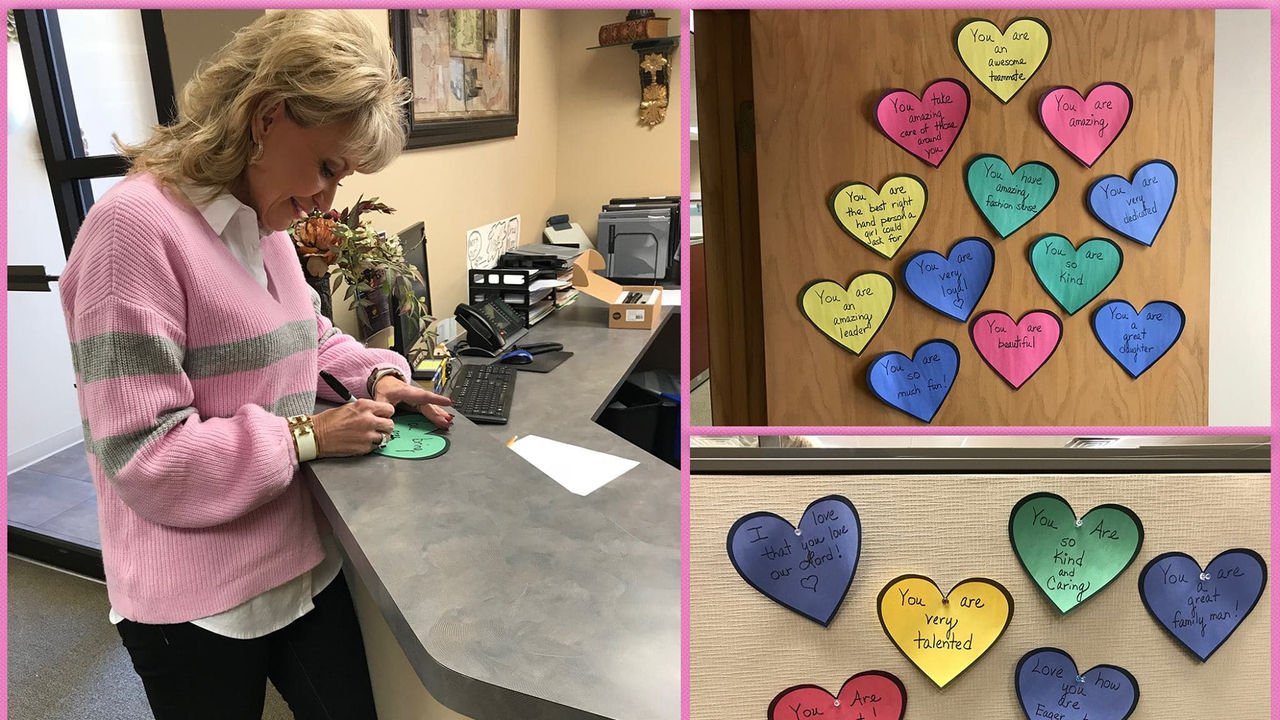 A woman is writing a note on a piece of paper with hearts on it.