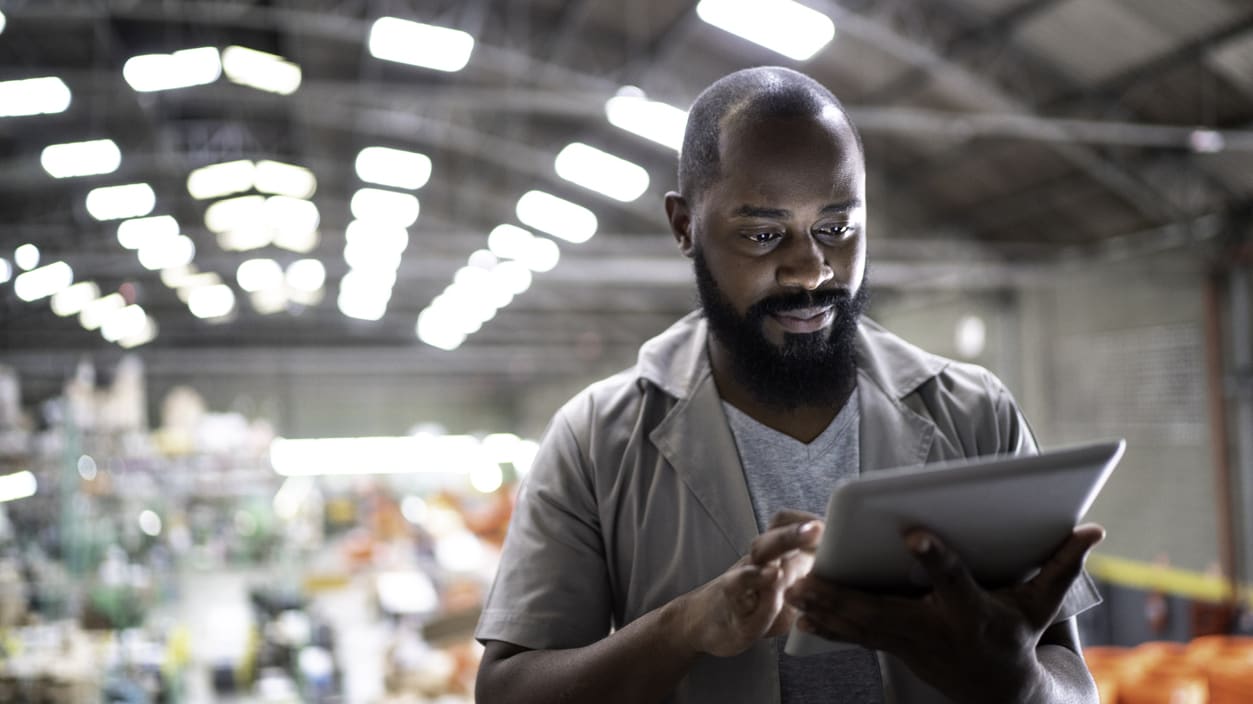 A man using a tablet in a warehouse.