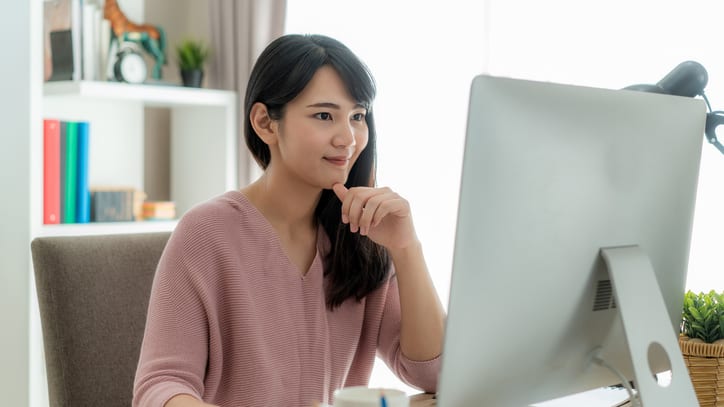 A young woman sitting in front of a computer smiling.