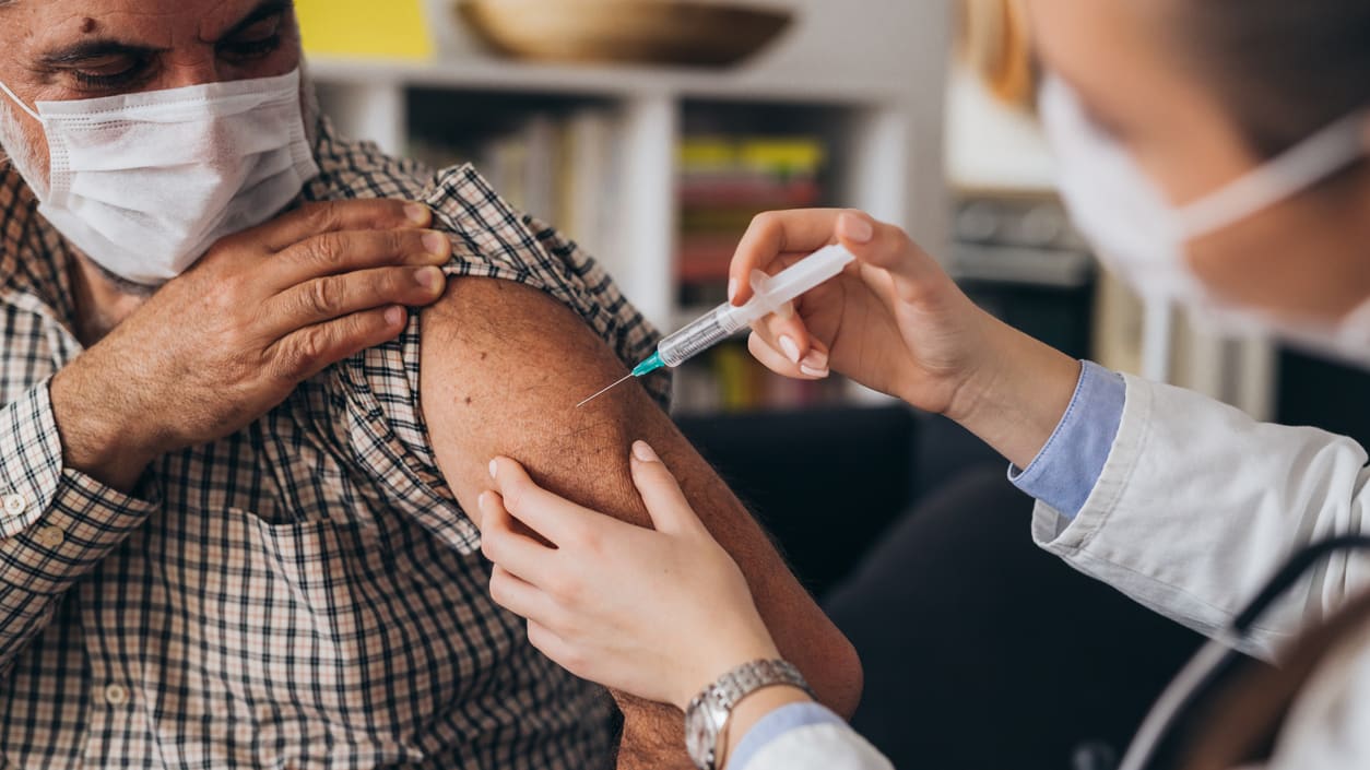 A man is getting a vaccine from a doctor.